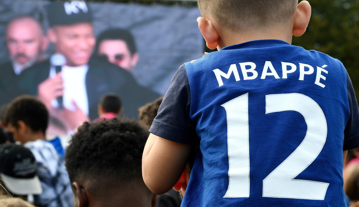 Seorang anak memakai jersey bernama bintang Prancis, Kylian Mbappe, saat jumpa fans markas AS Bondy di Paris, Rabu (17/10). Kunjungan ke klub pertamanya ini dilakukan setelah dirinya meraih gelar Piala Dunia 2018. (AFP/Franck Fife)