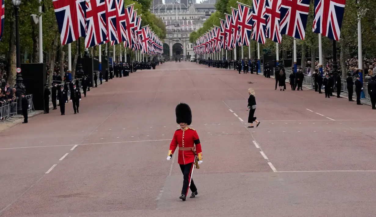 Seorang prajurit King's Guard melintasi The Mall di luar Istana Buckingham sebelum prosesi pemakaman Ratu Elizabeth II di pusat Kota London, Inggris, Senin (19/9/2022). Ratu Elizabeth II yang meninggal dalam usia 96 pada 8 September 2022, akan dimakamkan di Windsor bersama mendiang suaminya, Pangeran Philip, yang meninggal tahun lalu. (AP Photo/Christophe Ena, Pool)