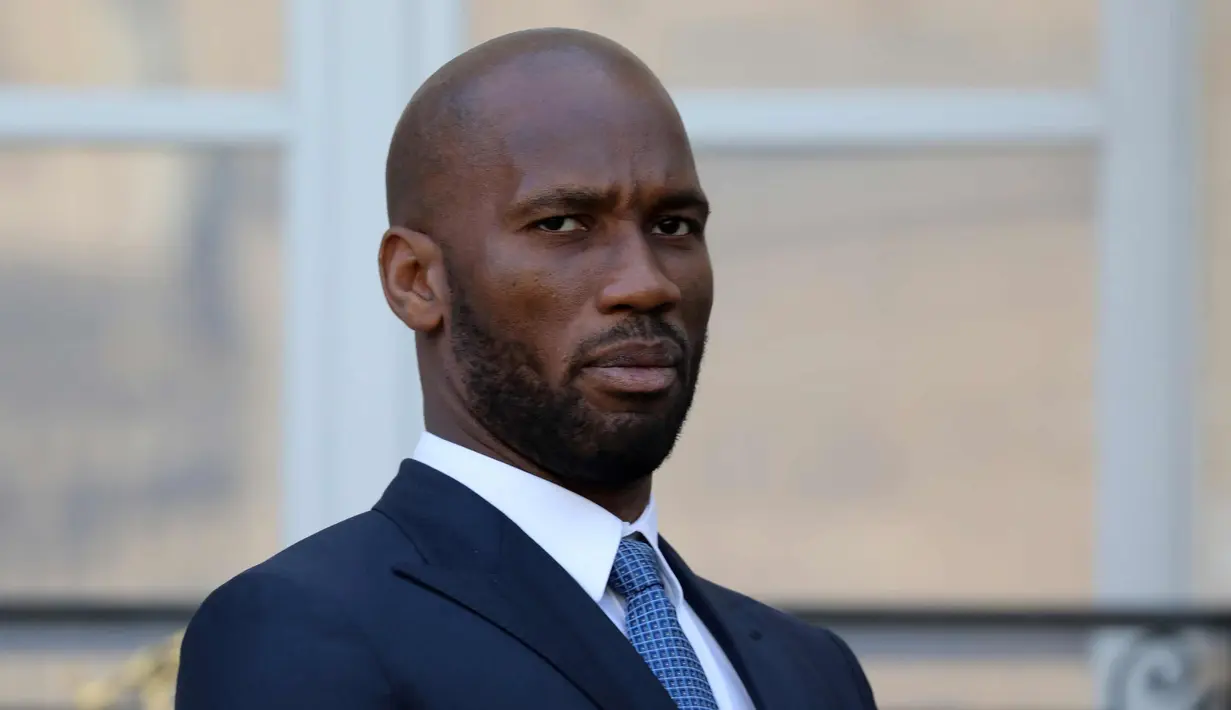Didier Drogba saat tiba menghadiri undangan makan siang Presiden Liberia George Weah dan Presiden Prancis Emmanuel Macron di Istana Elysee di Paris, (21/2). Mantan penyerang Chelsea ini tampil dengan setelan jas berwarna biru. (AFP Photo/Ludovic Marin)