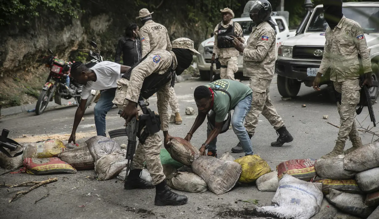 Pengemudi taksi membantu polisi menghilangkan penghalang jalan yang dibuat oleh pengunjuk rasa selama demonstrasi menuntut Perdana Menteri Haiti Ariel Henry mundur dan menyerukan kualitas hidup yang lebih baik, di Port-au-Prince, Haiti, Senin (29/8/2022). (AP Photo/Odelyn Joseph)
