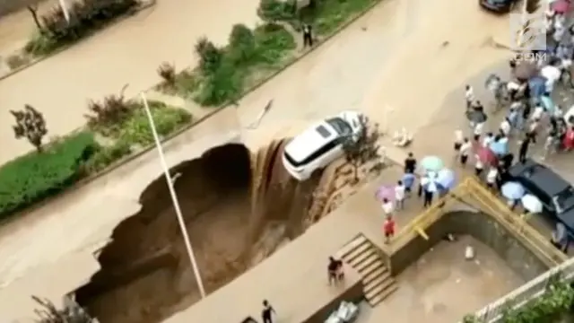 Sebuah mobil terseret arus banjir bandang hingga nyaris masuk ke dalam sinkhole di China. Warga bekerja sama menyelamatkan mobil tersebut.