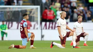 Pemain Burnley Zeki Amdouni beserta pemain Manchester City Erling Haaland dan Kevin De Bruyne berlutut menjelang pertandingan sepak bola Liga Inggris di Turf Moor, Burnley, Inggris, Jumat (11/8/2023). Manchester City menang 3-0. (Nigel French/PA via AP)