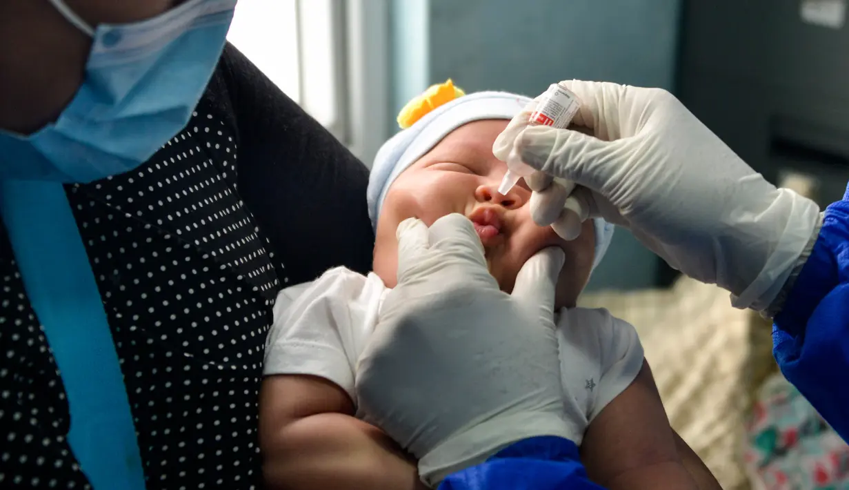 Seorang ibu menggendong bayinya saat petugas kesehatan memberikan vaksin polio di sebuah Pukesmas di Banda Aceh, Aceh, Senin (15/6/2020). Memasuki tatanan normal baru, pelayanan imunisasi anak kembali dibuka setelah sebelumnya sempat terhenti akibat pandemi COVID-19. (CHAIDEER MAHYUDDIN/AFP)