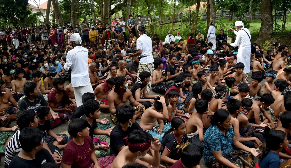Orang-orang menerima air suci saat mereka mengambil bagian dalam tradisi mandi lumpur yang dikenal sebagai Mebuug-buugan di Desa Kedonganan, Bali, 4 Maret 2022. Mebuug-buugan diadakan sehari setelah Nyepi yang bertujuan untuk menetralkan sifat buruk. (SONY TUMBELAKA/AFP)