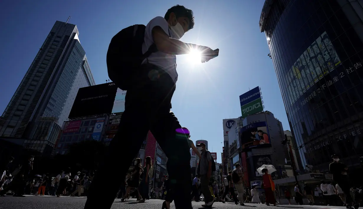 Pria yang memakai masker untuk mencegah penyebaran COVID-19 meyeberang jalan di Shibuya, Tokyo, Jepang, Jumat (3/7/2020). Jepang mengangkat darurat pandemi selama tujuh minggu pada akhir Mei, sebagian besar kegiatan sosial dan bisnis sejak itu telah kembali dimulai. (AP Photo/Eugene Hoshiko)