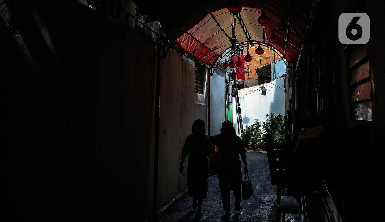 Warga melintasi hiasan menyambut Tahun Baru Imlek di Kawasan Petak Sembilan, Glodok, Jakarta, Minggu (7/2/2021). Dimulai dari kawasan Petak Sembilan, sejumlah Vihara mulai dihiasi lampion-lampion warna merah yang identik dengan Imlek. (Liputan6.com/Johan Tallo)