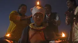 Seorang umat Hindu membawa lampu minyak selama perayaan pada hari kesepuluh festival Dashain di sebuah kuil di Bhaktapur di pinggiran Kathmandu, Nepal (15/10/2021). (AFP/Prakash Mathema)