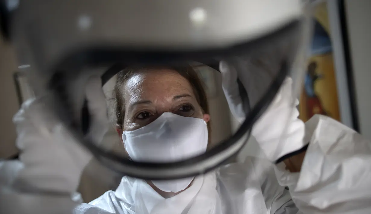 Istri akuntan Brasil Tercio Galdino, Alicea Galdino mengenakan helm saat akan pergi ke Pantai Copacabana dengan pakaian pelindung mirip astronaut di Rio de Janeiro, Brasil, 12 Juli 2020. Tercio membuat pakaian tersebut dari bahan yang digunakan oleh para profesional kesehatan. (Mauro Pimentel/AFP)