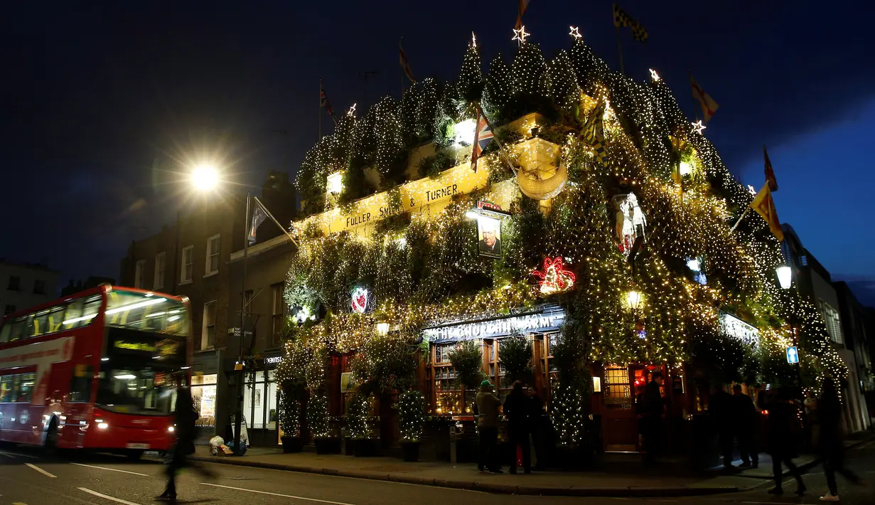 Pohon natal menutupi bagian luar bangunan bar The Churchill Arms di London, Inggris, 20 Desember 2016. Dalam rangka menyambut Natal, lebih dari 80 pohon natal dan hampir 22.000 lampu berkelap-kelip tampak menghiasi bar tersebut. (REUTERS/Neil Hall)