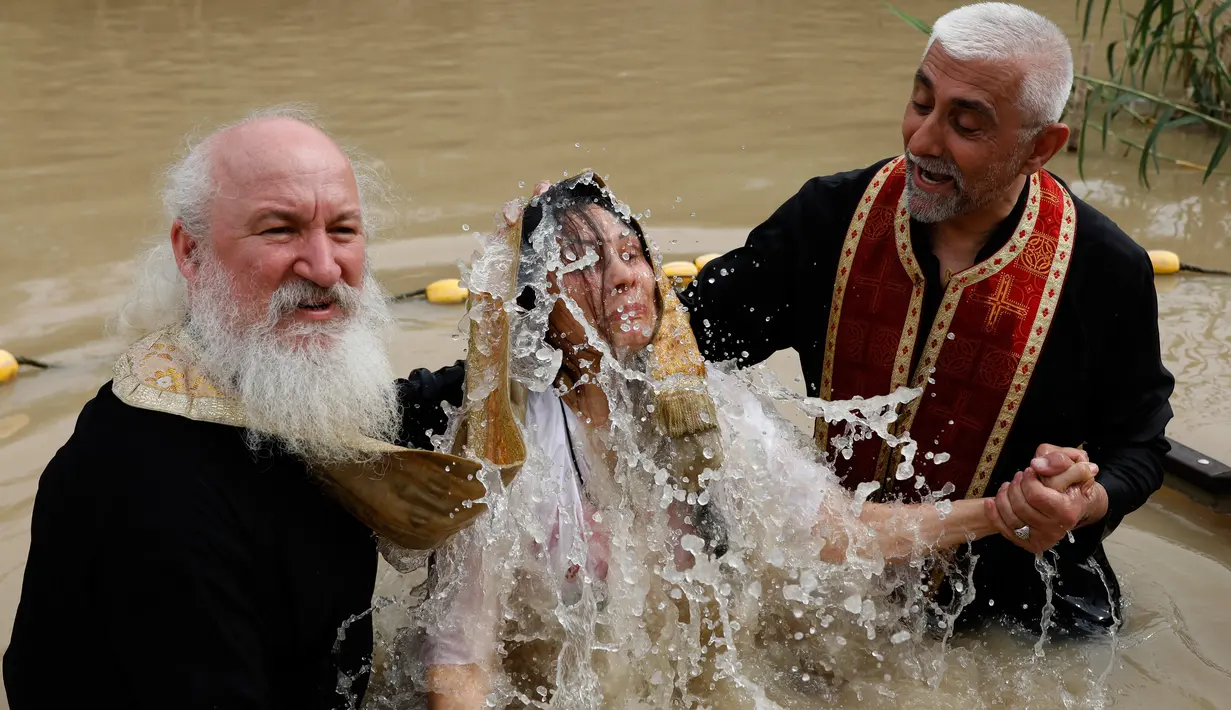 Seorang wanita Kristen Ortodoks Serbia dibaptis di perairan Sungai Yordan di dekat kota Jericho (4/3). Sungai ini diyakini menjadi tempat Yesus Kristus dibaptis oleh Yohanes Pembaptis. (AFP Photo/Gali Tibbon)