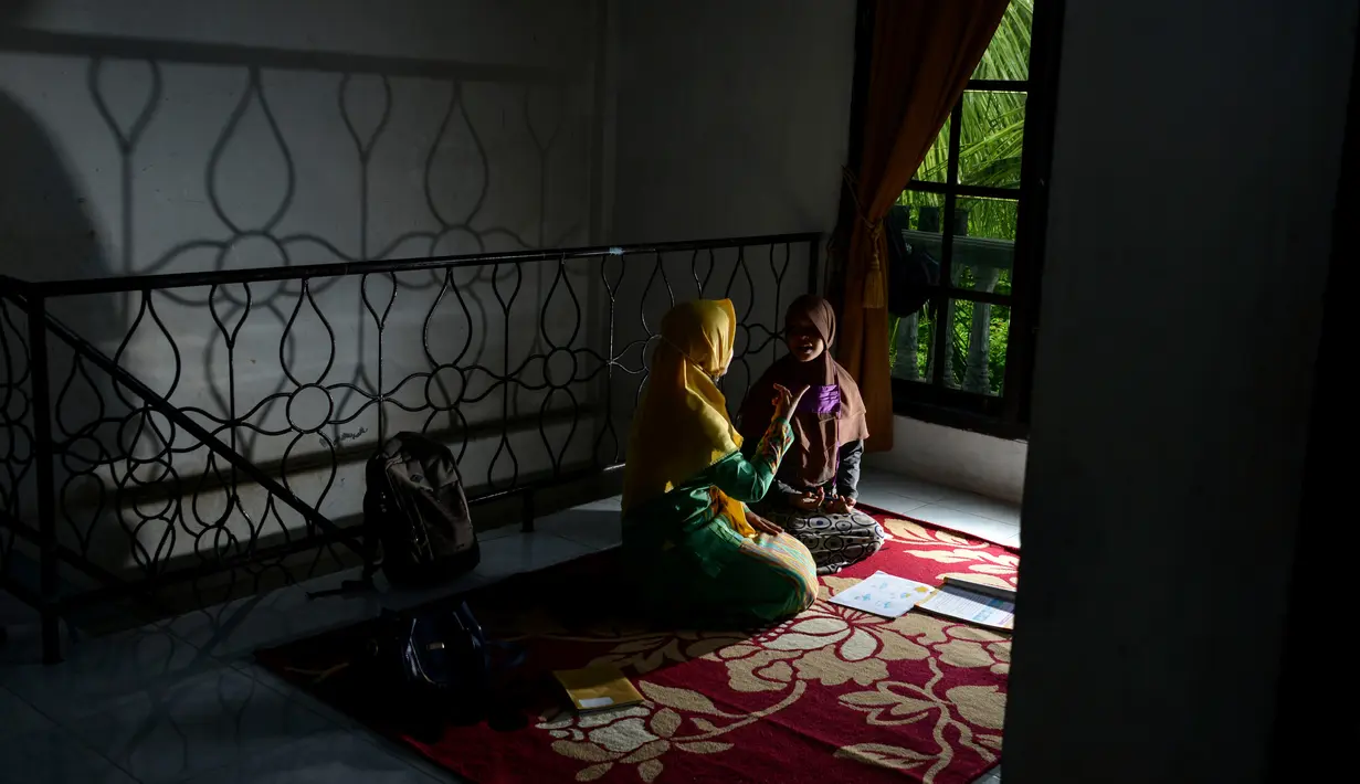 Seorang guru (kedua kiri) menggunakan bahasa isyarat membimbing siswa tunarungu di rumahnya di Pekan Bada, dekat Banda Aceh (14/9/2020). Para guru telah membimbing siswa yang kekurangan akses ke internet untuk kelas online di rumah mereka setelah wabah virus merebak. (AFP Photo/Chaideer Mahyuddin)