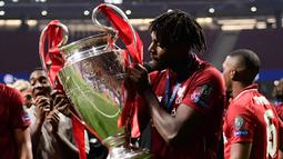 Selebrasi striker Liverpool, Divock Origi dengan trofi Liga Champions 2018/2019 dalam perayaan gelar juara setelah mengalahkan Tottenham Hotspur pada laga final di Wanda Metropolitano Stadium, Madrid (1/6/2019). Divock Origi mampu meraih trofi Liga Champions bersama Liverpool pada musim 2018/2019. Ia total tampil dalam 8 laga di Liga Champions musim 2018/2019 dengan mencetak 3 gol. Dua gol dicetaknya di leg kedua semifinal saat menang 4-0 atas Barcelona dan satu gol pada laga final saat menang 2-0 atas Tottenham Hotspur. (AFP/Javier Soriano)