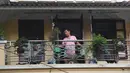 Gambar pada 3 September 2021 menunjukkan seorang pria menyirami tanaman di balkon rumahnya di Hanoi, Vietnam, selama lockdown Covid-19. Menghadap ke jalan yang sepi, balkon kecil mereka menjadi saksi bisu terkait aktivitas yang dilakukan oleh masing-masing keluarga. (Nhac NGUYEN/AFP)