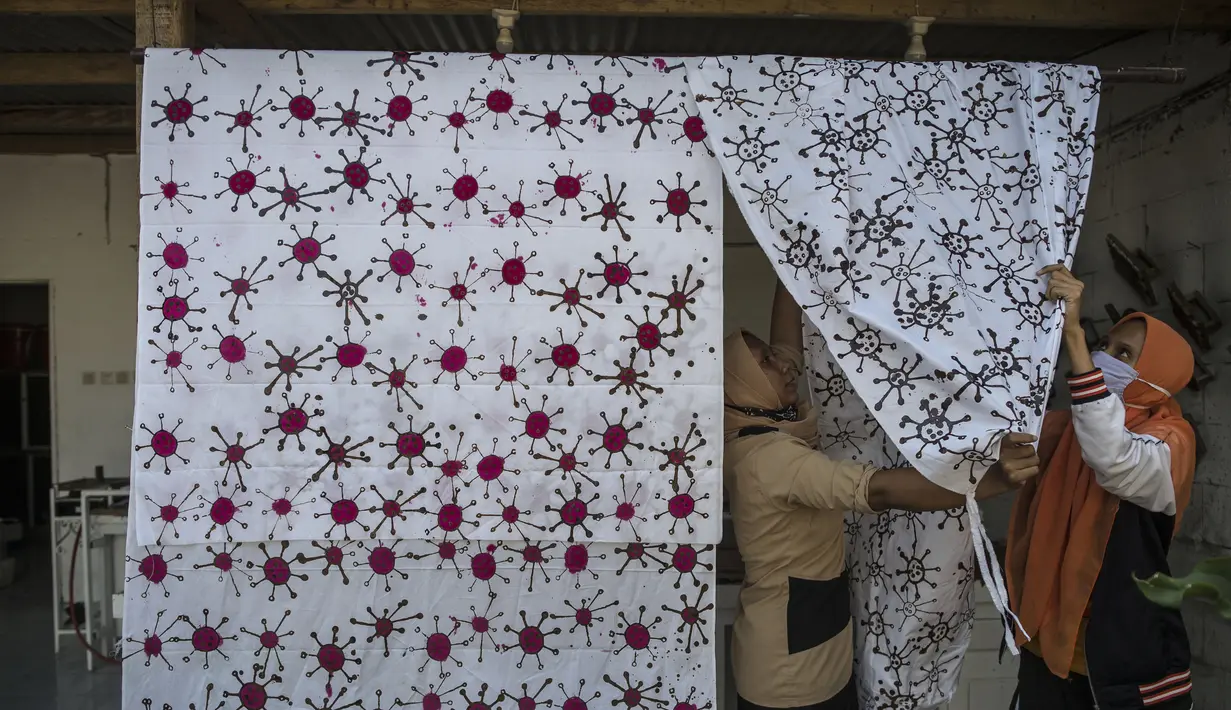 Penyandang disabilitas menjemur kain batik dengan motif virus corona di Surabaya, Jawa Timur (19/8/2020). Di tengah pandemi Covid-19, sekelompok penyandang disabilitas di Surabaya membuat batik bermotifkan virus corona. (AFP/JUNI KRISWANTO)