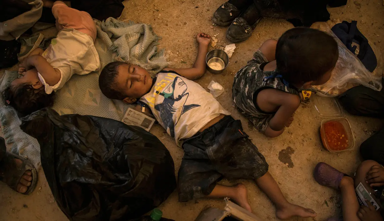 Sejumlah anak keluarga militan ISIS tertidur saat menunggu untuk meninggalkan kamp penampungan al-Hol di Provinsi Hasakeh, Suriah, Senin (3/6/2019). Sebagian anak-anak ini dipulangkan ke Raqqa, kota yang pernah menjadi Ibu Kota ISIS. (AP Photo/Baderkhan Ahmad)