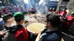 Koki bersiap menuangkan kacang lentil rebus ke panci raksasa untuk memecahkan rekor dunia Guinness Record dalam acara Prado Rural di Montevideo, Uruguay, Minggu (13/9/2015). Kacang tersebut cukup untuk memberi makan 10.000 orang. (AFP PHOTO/Miguel Rojo)