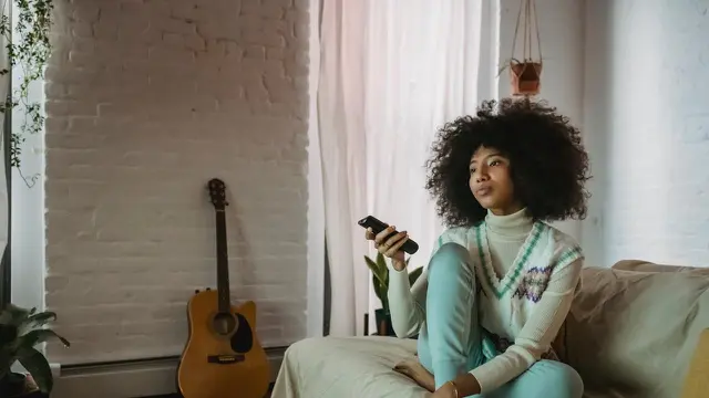 Memegang remot tv (Pexels)