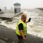 Seorang pekerja utilitas memotret ombak saat mereka menabrak tembok laut di marina kota saat band luar Badai Ida tiba di Bay Saint Louis, Miss (29/8/2021). Menurut Gubernur Louisiana John Bel Edwards, Ini adalah salah satu badai terkuat yang mendarat di sini di zaman modern. (AP Photo/Steve Helber)