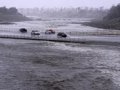 Kendaraan melintasi cekungan pengendali banjir yang hampir mencapai jalan di Palm Desert, California, Minggu, 20 Agustus 2023.(AP Photo/Mark J. Terrill)