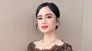 Siluet kebaya yang fitted mengikuti lekuk tubuhnya mempertegas kesan feminin, sementara aksen transparan di bagian lengan memberi sentuhan modern yang ringan. Bagian depan kebaya dibuat dengan potongan klasik lengkap dengan detail kancing yang memperkuat nuansa tradisional.