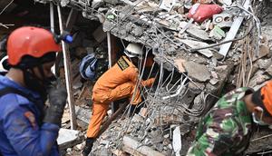 Tim penyelamat mencari korban di sebuah bangunan yang runtuh di kota Mamuju, Sulawesi Barat, Sabtu (16/1/2021). Jalan dan jembatan yang rusak, pemadaman listrik, dan kurangnya alat berat menghambat evakuasi setelah gempa bermagnitudo 6,2 SR yang melanda Majene- Mamuju. (Hariandi Hafid/AFP)