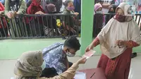 Warga menerima uang Bantuan Sosial Tunai (BST) bulan Januari di halaman Masjid Jami Al-Hidayah RW 01 Bedahan, Depok, Selasa (16/2/2021). Sekitar 159.470 Keluarga Penerima Manfaat (KPM) di Kota Depok menerima BST yang disalurkan PT Pos Indonesia pada Februari ini. (merdeka.com/Arie Basuki)