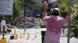 Warga melihat petugas pemadam yang tengah bekerja di reruntuhan apartemen di Sivler Spring, Maryland, Washington DC, Kamis (11/8). Ledakan terjadi akibat adanya kebocoran antara pipa gas yang mengaliri apartemen itu dengan kompor. (REUTERS/Joshua Roberts)