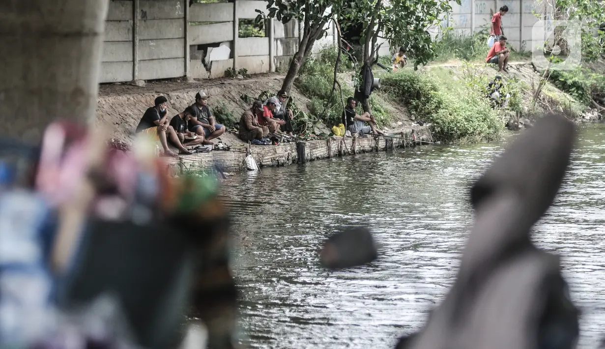 Warga memancing di waduk kawasan Sungai Bambu, Tanjung Priok, Jakarta, Minggu (17/1/2021). Waduk buatan yang tepat berada di bawah Jalan Tol Pelabuhan tersebut menjadi wisata alternatif menghabiskan akhir pekan tanpa mengeluarkan biaya atau gratis. (merdeka.com/Iqbal S. Nugroho)