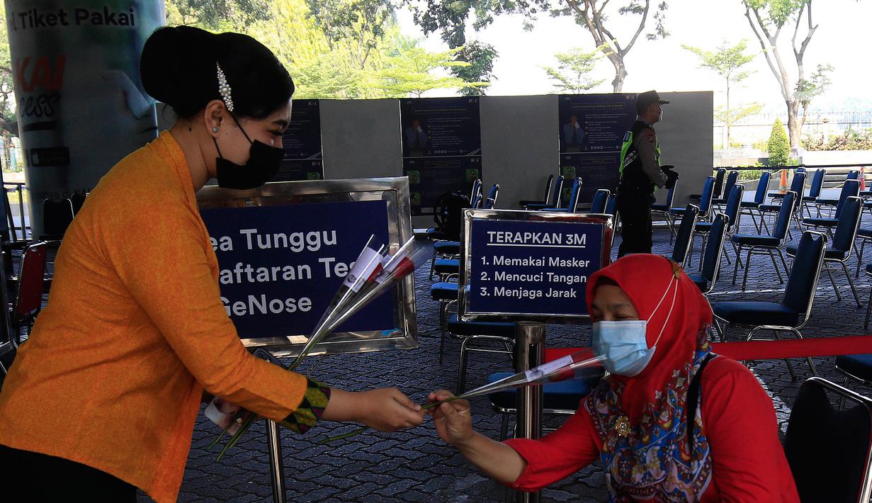 Petugas PT KAI Daop 1 Jakarta membagikan bunga kepada penumpang di Stasiun Gambir, Rabu (21/4/2021). PT KAI DAOP 1 memperingati Hari Kartini menginspirasi para penumpang agar semangat berjuang melawan pandemi COVID-19 dengan selalu menerapkan protokol kesehatan. (Liputan6.com/Herman Zakharia)
