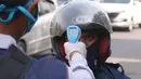 Petugas memeriksa suhu tubuh pengendara saat pelaksanaan Pembatasan Sosial Berskala Besar (PSBB) di kawasan Gading Serpong, Tangerang Selatan, Sabtu (18/4/2020). Pengukuran suhu tubuh tersebut merupakan cek point dari PSBB yang baru saja diberlakukan di Tangerang Raya. (Liputan6.com/Angga Yuniar)