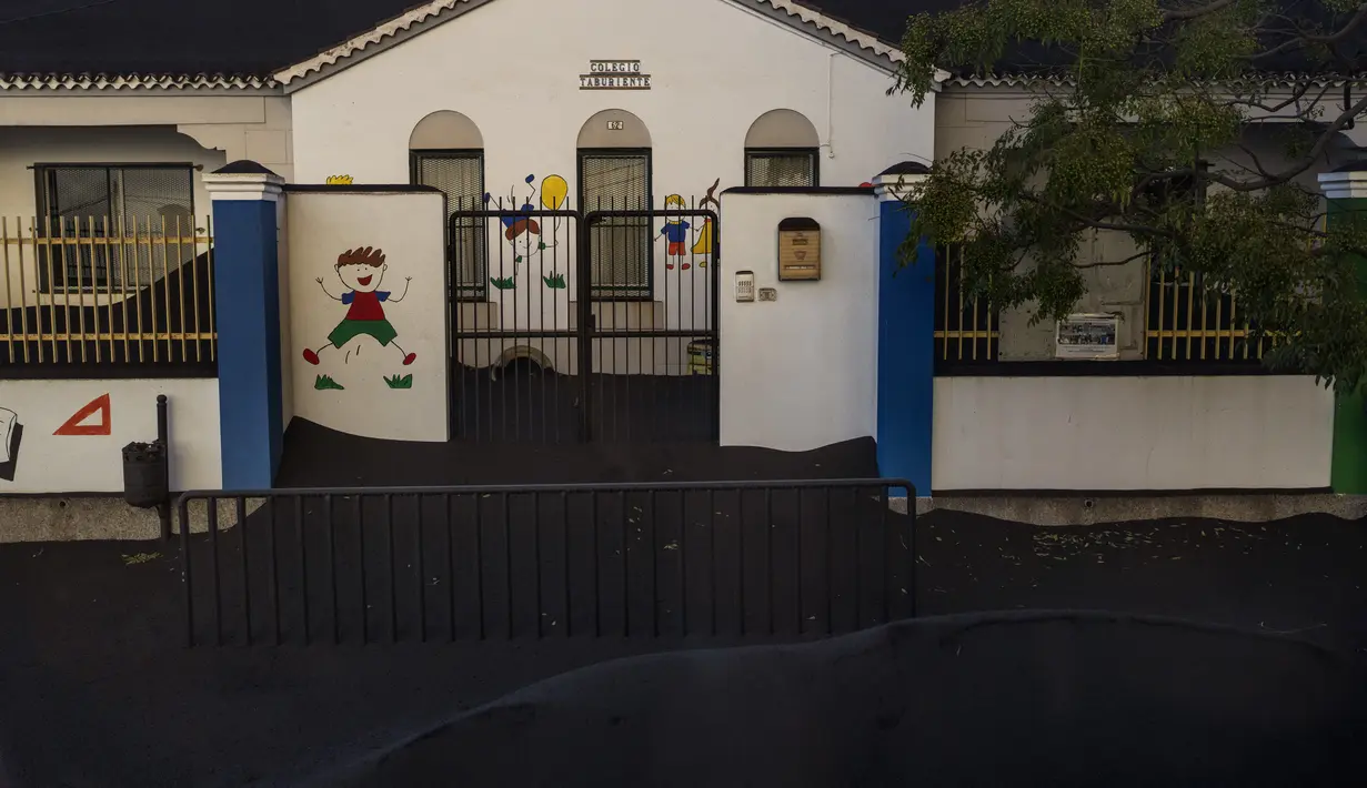 Pintu masuk sekolah tertutup abu gunung Cumbre Vieja di Las Manchas de Abajo di pulau Canary La Palma, Spanyol, Rabu (27/10/2021). Penduduk di Pulau La Palma menghadapi kemungkinkan gempa yang lebih kuat yang bisa memperparah kerusakan oleh muntahan lava gunung tersebut. (AP Photo/Emilio Morenatti)