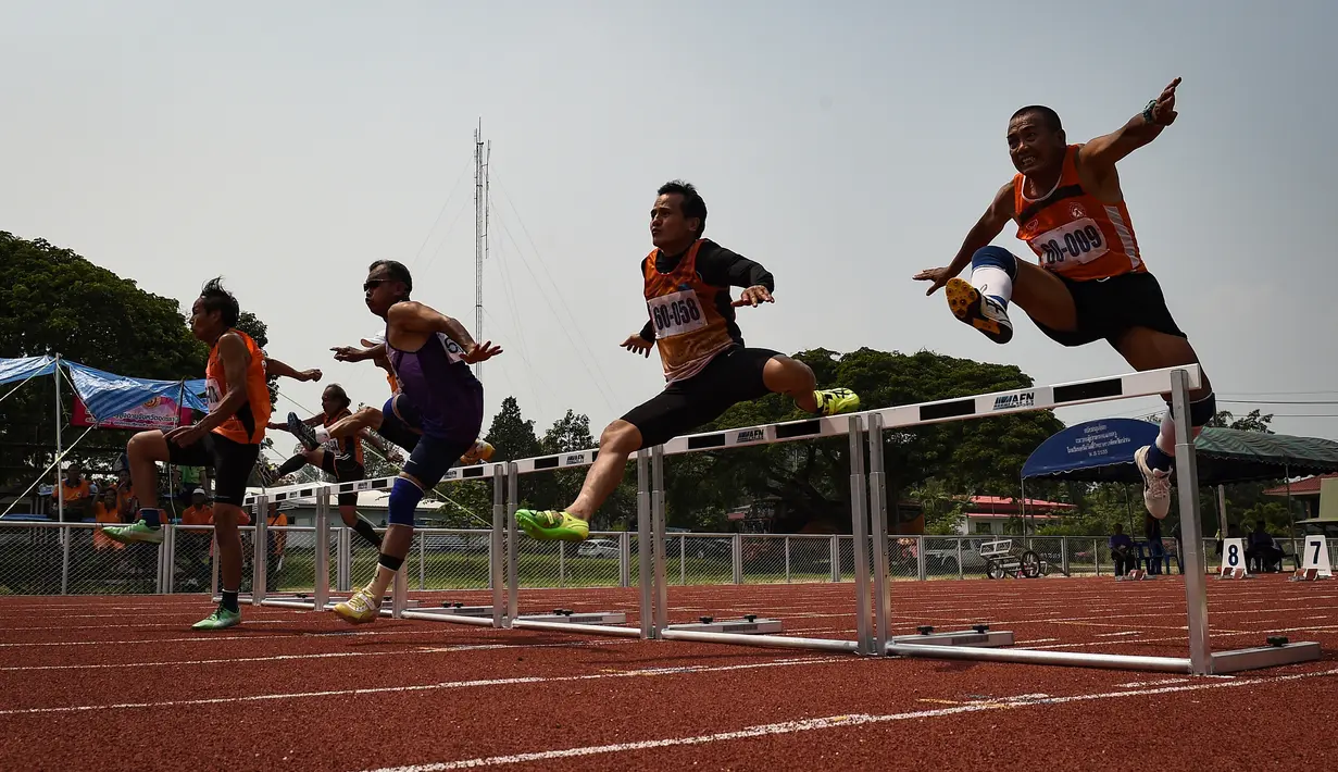 Para peserta melompat saat mengikuti lomba lari ringtangan 100 meter dalam Elderly Games nasional di Thailand (25/4). Peserta lomba lari ringtangan 100 meter merupakan pria yang berusia antara 60-65 tahun. (AFP/Lillian Suwanrumpha)