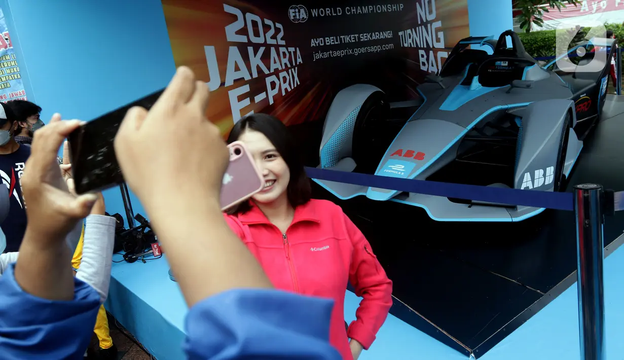 Warga berfoto dengan latar replika mobil Formula E yang dipamerkan di Kawasan Bundaran Hotel Indonesia, Jakarta, Minggu (29/5/2022). Replika mobil balap ramah lingkungan ini dipamerkan untuk mengkampanyekan perhelatan Formula E yang akan digelar 4 Juni mendatang. (Liputan6.com/Helmi Fithriansyah)