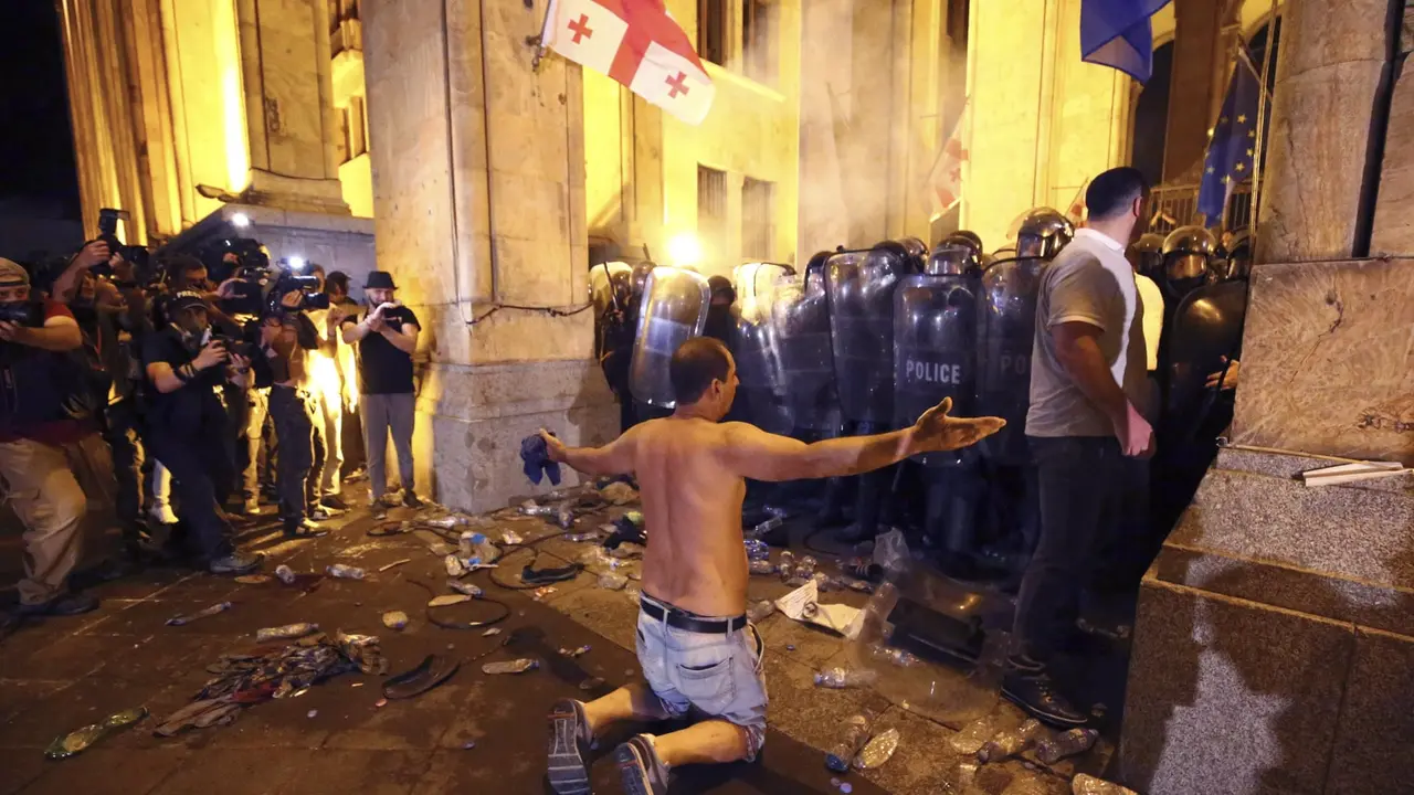 Seorang demonstran tampak berlutut di hadpaan polisi setelah bentrok menyebabkan 30 orang terluka (AP/ Zurab Tsertsvadze)