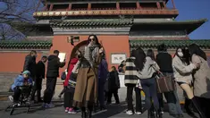 Seorang perempuan berswafoto dengan haw China berlapis gula saat pengunjung berkumpul di luar Menara Drum di Beijing, Senin (30/1/2023). Orang-orang China menikmati Tahun Baru Imlek dan mengunjungi berbagai lokasi wisata di kota-kota di sekitar China setelah pencabutan pembatasan COVID-19 yang kejam bulan lalu, memungkinkan banyak aspek kehidupan normal kembali. (AP Photo/Andy Wong)