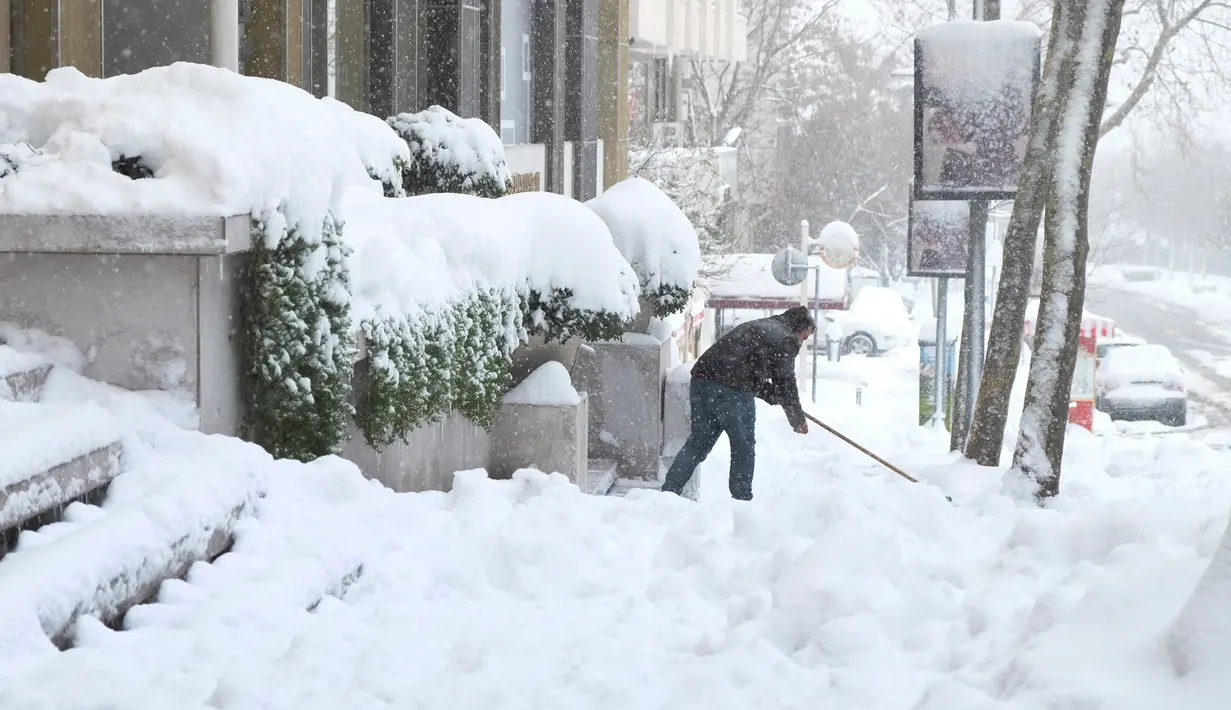 Seorang pria membersihkan salju tebal yang menutupi teras rumahnya di Istanbul, Turki, Sabtu (7/1). Badai salju dahsyat melumpuhkan aktivitas warga dengan ratusan jadwal penerbangan tertunda. (AP Photo/Mike Gorder)