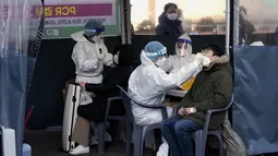 Petugas medis mengambil sampel usap hidung dari orang-orang di tempat pengujian darurat di Seoul, Korea Selatan, Rabu (23/2/2022). Kasus harian COVID-19 baru Korea Selatan mencapai rekor tertinggi, melonjak menjadi 171.452 dari 99.569 kasus sehari sebelumnya. (AP Photo/Ahn Young-joon)