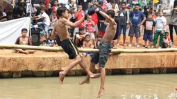 Anak-anak bermain lomba pukul bantal di sekitar Kalimalang, Jakarta, Sabtu (17/8/2019). Beragam lomba permainan digelar warga untuk menyemarakkan HUT ke-74 Republik Indonesia. (Liputan6.com/Helmi Fithriansyah)