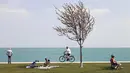 Orang-orang memanfaatkan cuaca musim semi yang hangat di sepanjang Danau Michigan, Chicago, Selasa (27/4/2021). Warga AS yang telah menerima vaksin COVID-19 tidak lagi diwajibkan mengenakan masker saat berada di luar ruangan kecuali berada di tengah kerumuman orang asing. (AP Photo/Shafkat Anowar)