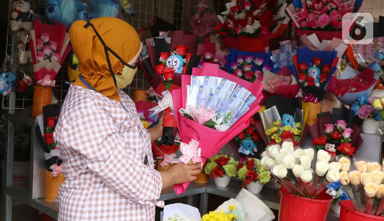 Penjual menujukkan bunga mawar yang dihias dengan boneka,uang dan coklat di Rawa Belong, Jakarta, Senin (14/2/2022). Hari Valentine yang diperingati setiap 14 Februari menjadi berkah bagi para penjual bunga karena banyak pesanan bunga di momen kasih sayang tersebut. (Liputan6.com/Angga Yuniar)