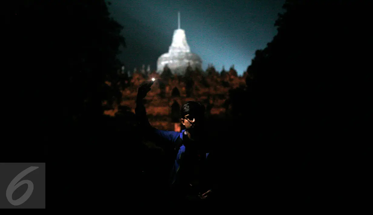 Seorang wisatawan menyalakan lilin dengan latar belakang Candi Borobudur saat dilaksanakan program Earth Hour atau peringatan Hari Bumi oleh WWF, UNESCO dan Balai Konservasi Borobudur, Magelang, Jawa Tengah, Sabtu (19/3) malam. (Foto: Boy Harjanto)