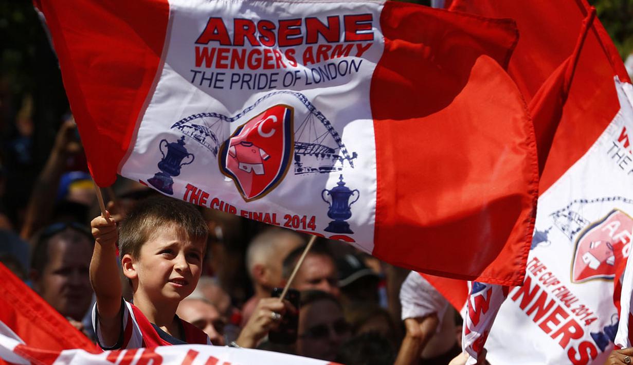 Salah satu suporter cilik "The Gunners" terus mengibarkan bendera saat menyaksikan parade kemenangan Arsenal di London, Inggris, (18/5/2014). (REUTERS/Andrew Winning)