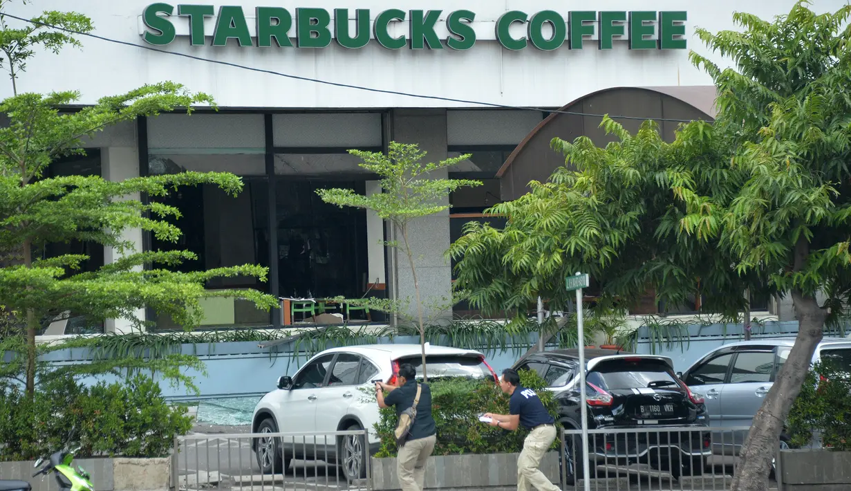 Polisi berpakaian preman mengarahkan senjata ke pelaku yang bersembunyi di dalam kafe pasca ledakan di pospol Sarinah, Jakarta, Kamis (14/1). Baku tembak terjadi di depan Sarinah setelah suara ledakan ketiga terjadi.  (AFP PHOTO/Bay Ismoyo)