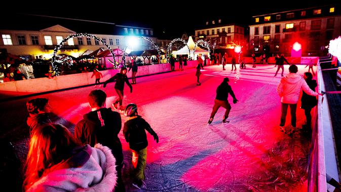 Pengunjung bermain di arena es yang ada di pasar Natal tradisional Kota Tua Heidelberg, Jerman, Selasa (4/12). Pasar Natal tradisional ini terletak di bawah kastil terkenal. (AP Photo/Michael Probst).