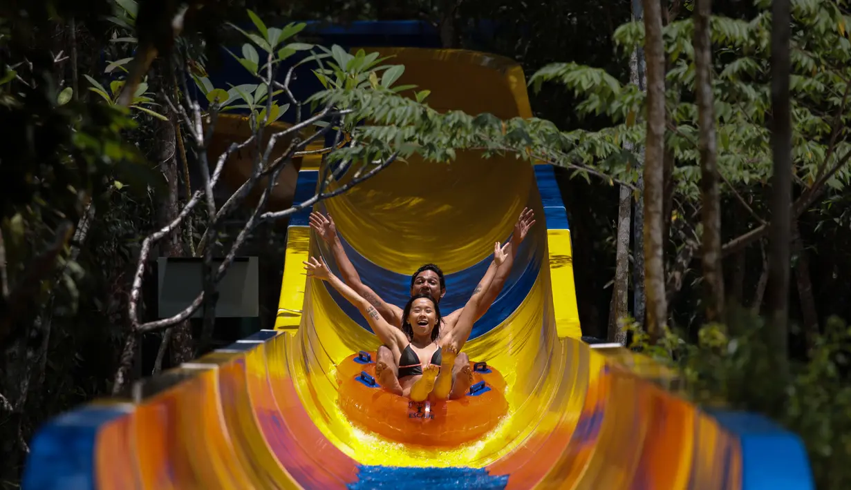 Pengunjung menggunakan pelampung meluncur di perosotan air terpanjang di dunia di Escape theme park di Teluk Bahang, Malaysia (25/9/2019). Pembangunan perosoton terpanjang di dunia ini dilakukan tanpa melakukan penebangan pohon. (AFP Photo/Sadiq Asyraf)
