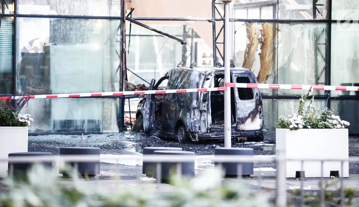 Sebuah mobil van hangus setelah menabrak pintu depan gedung tempat surat kabar ternama Belanda, De Telegraaf di Amsterdam, Selasa (26/6). Polisi menduga, tabrakan itu disengaja tetapi pengemudi minibus berhasil melarikan diri. (KOEN VAN WEEL/ANP/AFP)