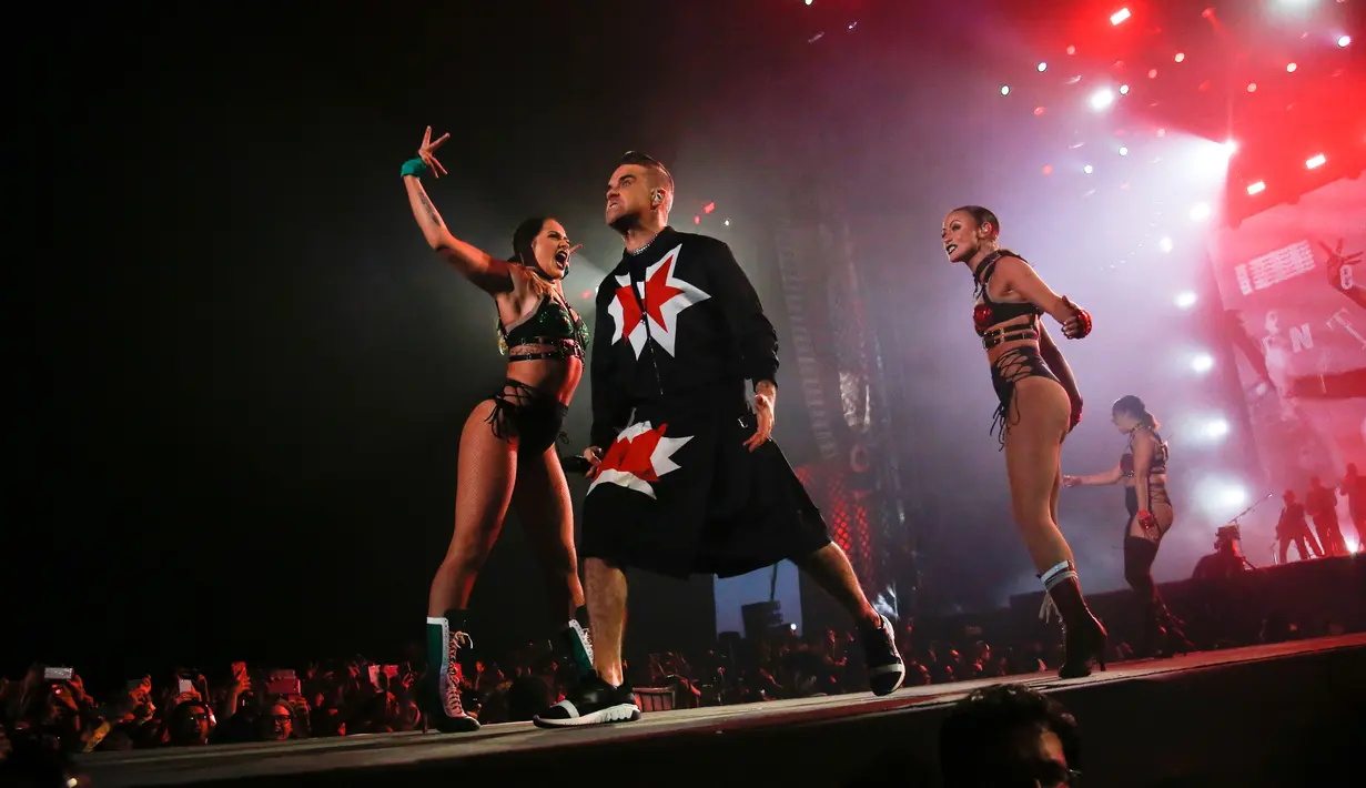 Aksi panggung Robbie Williams bersama para penari di Festival Musik Corona Capital di Meksiko (17/11). Pria 44 tahun ini tampil energik mengenakan setelan jas hitam dan rok yang dihiasi bintang merah. (AP Photo/Eduardo Verdugo)