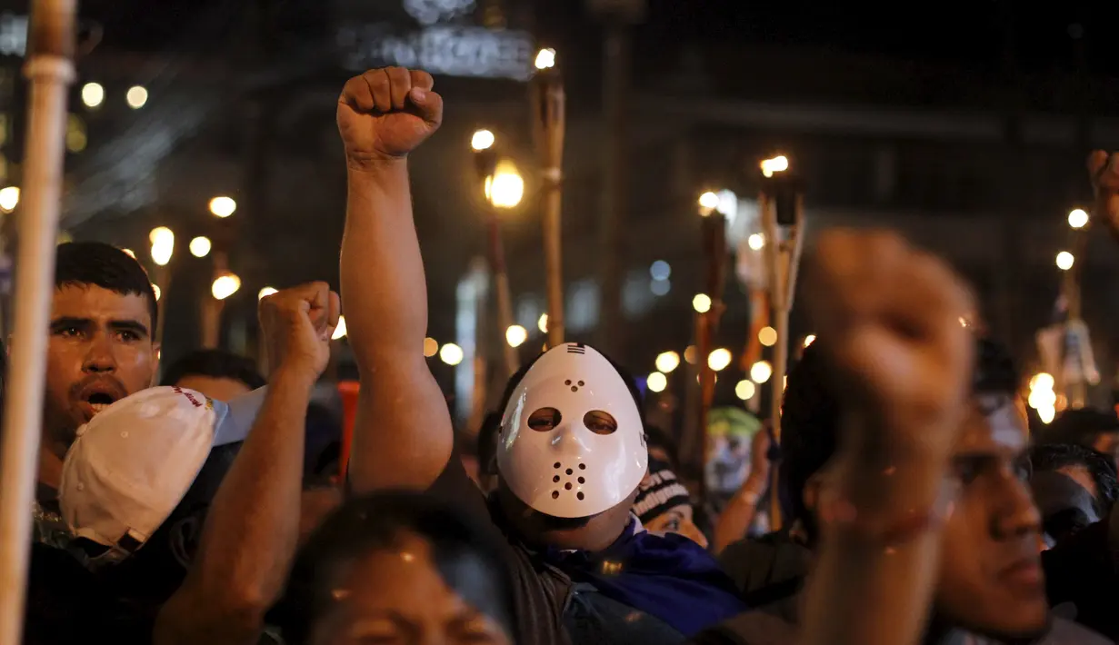 Seorang demonstran memakai masker saat unjuk rasa di Tegucigalpa, Jumat (24/7/2015).  Massa menuntut Presiden Juan Hernandez turun atas dugaan korupsi. (REUTERS/Jorge Cabrera)