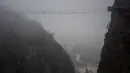 Wisatawan melewati jembatan gantung yang terbuat dari kaca di pegunungan Shinuizhai, Provinsi Hunan, Tiongkok, 6 Oktober 2015. Jembatan dengan panjang 300 m dan tinggi 180 m ini kembali dibuka setelah direnovasi untuk objek wisata. (AFP/Johannes Eisele)