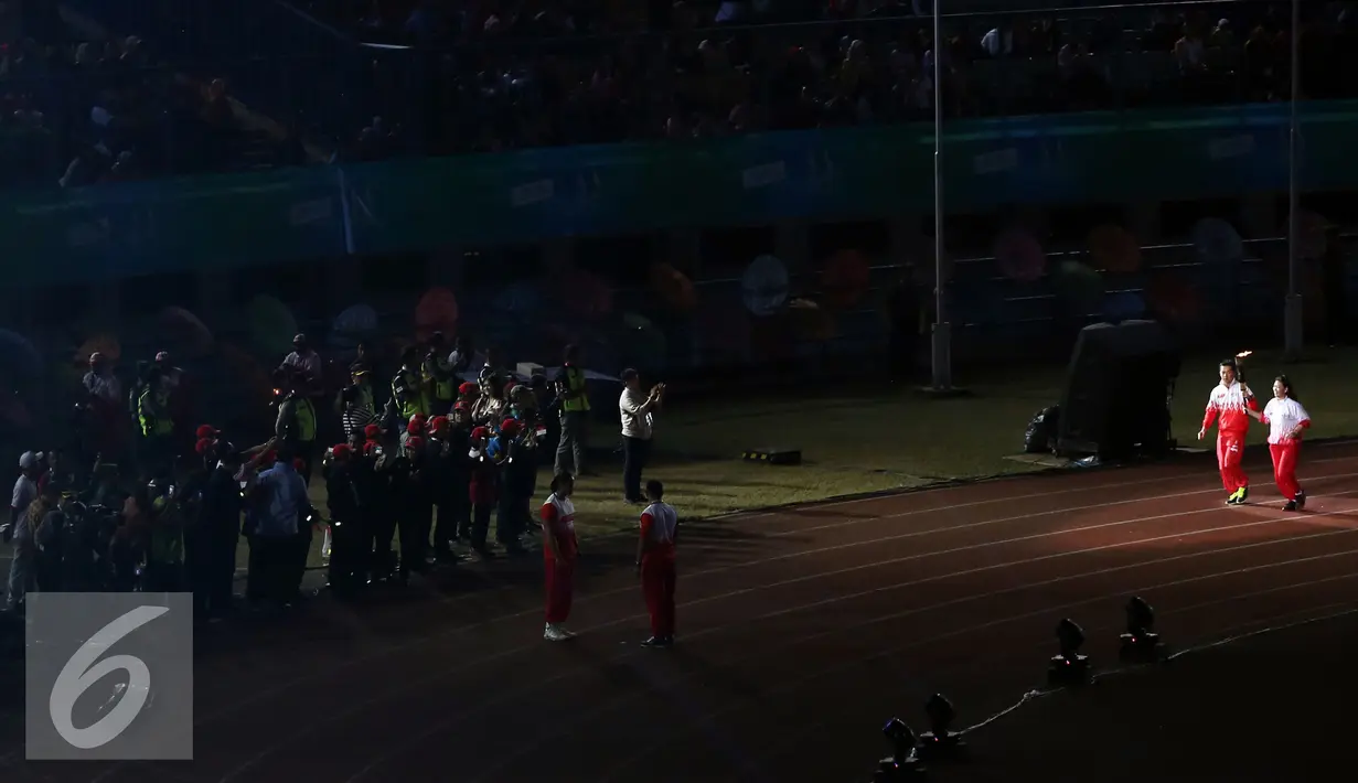 Susi Susanti (kanan) dan Taufik Hidayat disambut puluhan atlet kontingen saat membawa obor api PON XIX Jabar di Stadion Gelora Bandung Lautan Api, Bandung, Sabtu (17/9). PON XIX Jabar berlangsung hingga 29 September. (Liputan6.com/Helmi Fithriansyah)